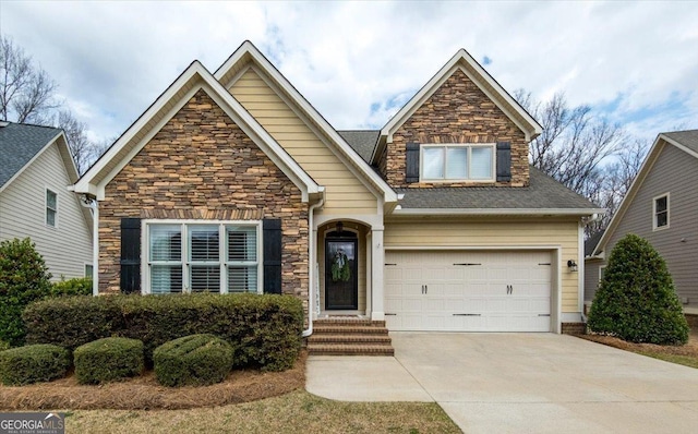 view of front of house featuring stone siding, a shingled roof, and concrete driveway