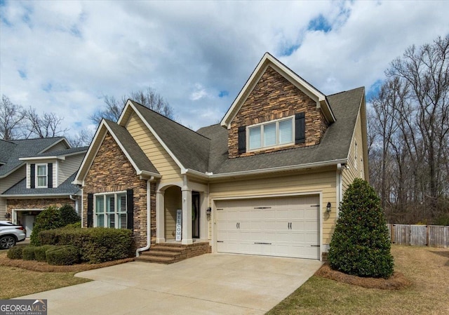 view of front facade featuring driveway, stone siding, fence, and roof with shingles