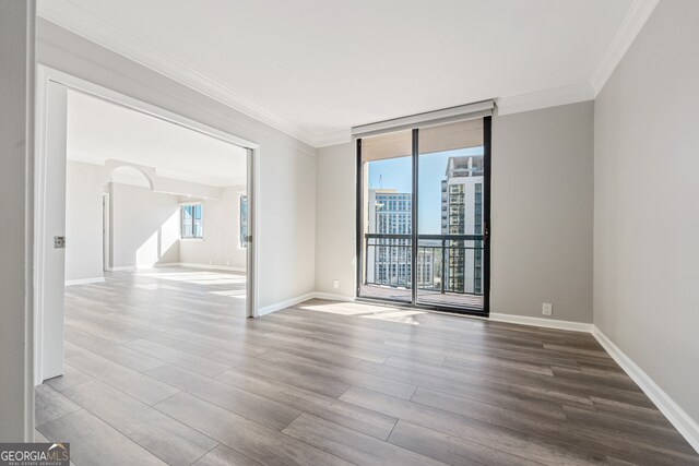 3481 Lakeside Dr NE Unit 2303, Atlanta, GA 30326 - spare room featuring baseboards, wood finished floors, arched walkways, and ornamental molding