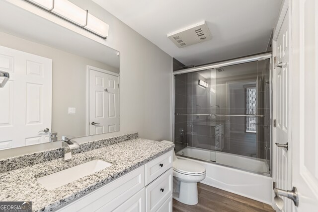 3481 Lakeside Dr NE Unit 2303, Atlanta, GA 30326 - bathroom featuring vanity, wood finished floors, visible vents, enclosed tub / shower combo, and toilet