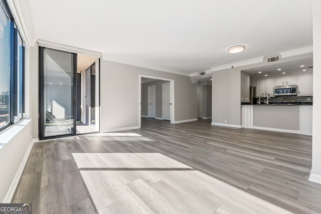 3481 Lakeside Dr NE Unit 2303, Atlanta, GA 30326 - unfurnished living room with crown molding, baseboards, visible vents, and light wood finished floors