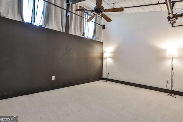 carpeted empty room featuring ceiling fan, high vaulted ceiling, and baseboards