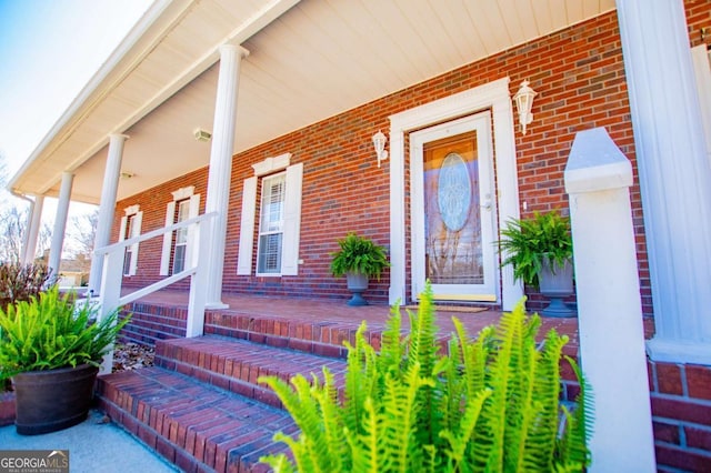 view of exterior entry with covered porch and brick siding