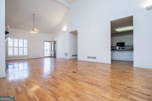 unfurnished living room with visible vents, ceiling fan, light wood-type flooring, beamed ceiling, and baseboards