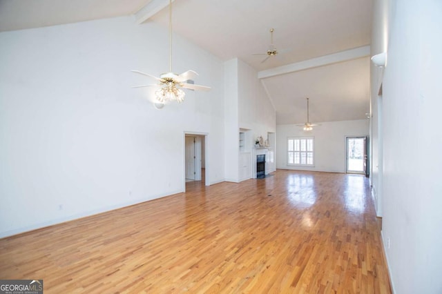 unfurnished living room with ceiling fan, a fireplace, baseboards, light wood-style floors, and beam ceiling