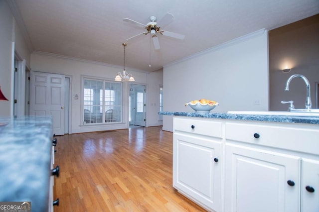 kitchen with ornamental molding, light wood-type flooring, a sink, and white cabinetry