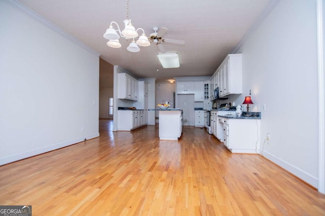 kitchen with light wood-style flooring, baseboards, white cabinets, stainless steel microwave, and dark countertops