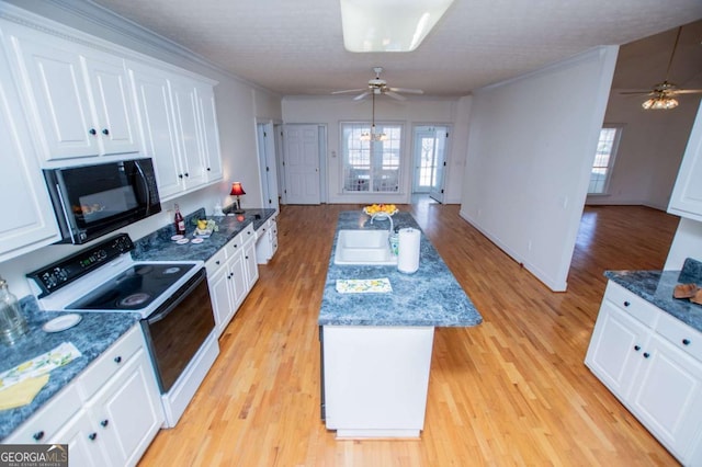 kitchen featuring black microwave, a sink, white cabinetry, a center island, and electric range oven