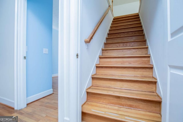 staircase featuring wood finished floors and baseboards