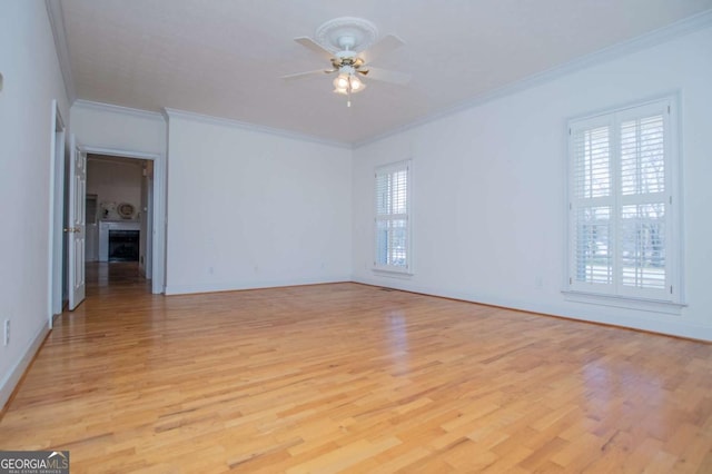 spare room featuring a healthy amount of sunlight, light wood-style flooring, a ceiling fan, and crown molding