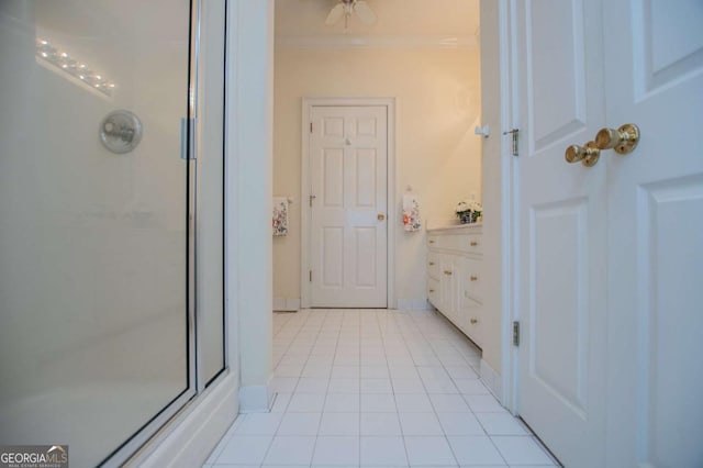 bathroom featuring tile patterned floors, crown molding, baseboards, and an enclosed shower