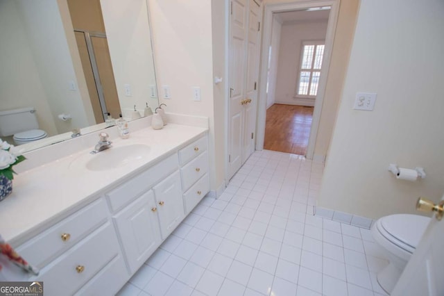 bathroom with toilet, vanity, baseboards, and tile patterned floors