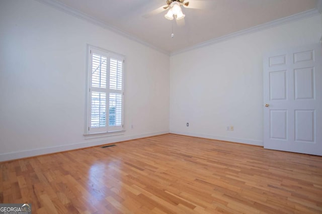 empty room with light wood finished floors, visible vents, ornamental molding, a ceiling fan, and baseboards