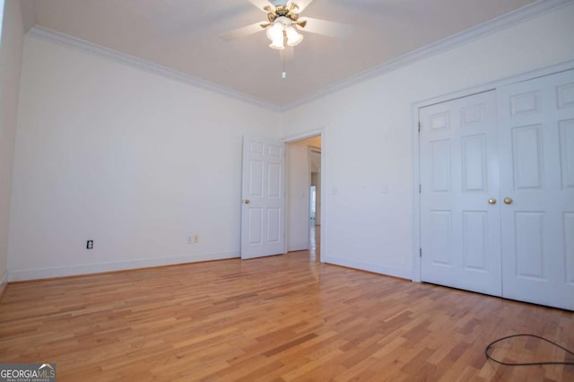 unfurnished bedroom with crown molding, light wood finished floors, a closet, ceiling fan, and baseboards