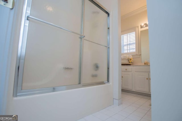 bathroom featuring combined bath / shower with glass door, ornamental molding, tile patterned flooring, and vanity