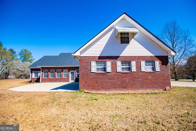 view of home's exterior with a patio area, brick siding, and a yard