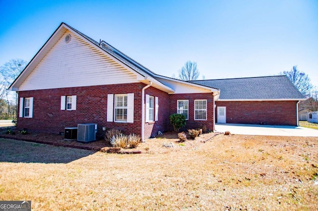 view of front of home featuring a patio area, brick siding, a front lawn, and central AC unit