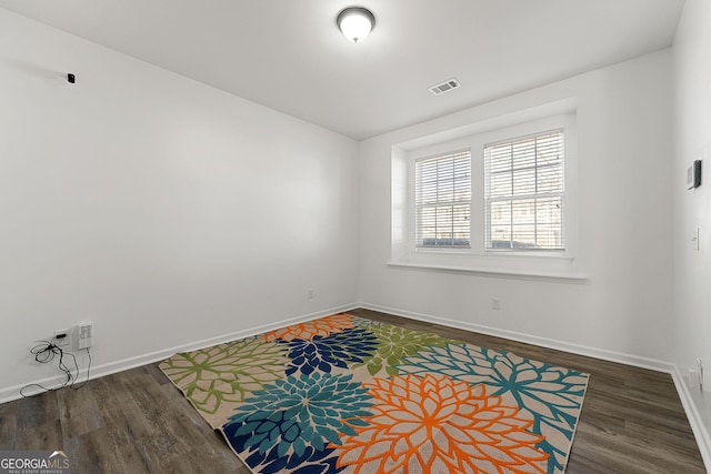 empty room with baseboards, visible vents, and wood finished floors