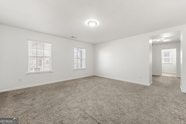 carpeted spare room featuring visible vents and baseboards