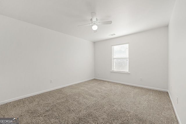 empty room with ceiling fan, carpet floors, visible vents, and baseboards