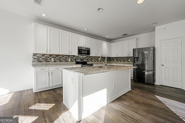 kitchen with appliances with stainless steel finishes, dark wood-style flooring, light stone countertops, white cabinetry, and a sink