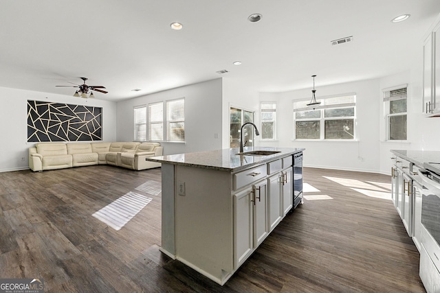 kitchen featuring stone counters, dark wood-style floors, visible vents, and a sink