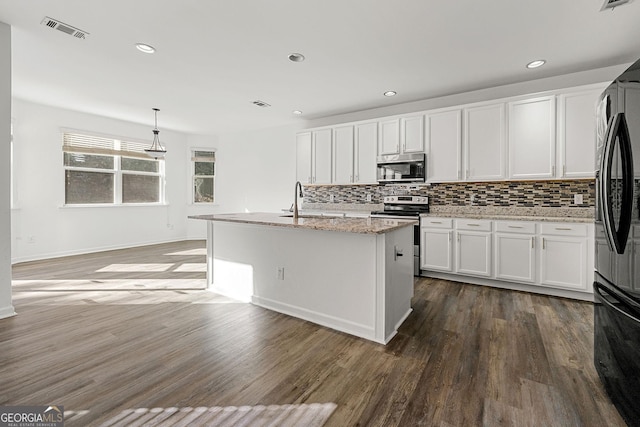 kitchen featuring stainless steel appliances, visible vents, decorative backsplash, white cabinets, and wood finished floors