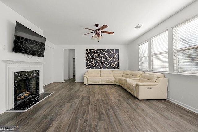 unfurnished living room with baseboards, visible vents, ceiling fan, wood finished floors, and a high end fireplace