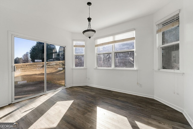 unfurnished dining area with baseboards and wood finished floors