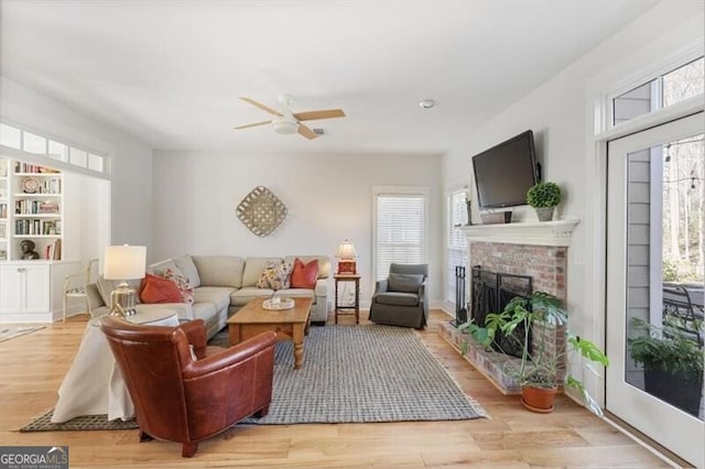 living area with ceiling fan, wood finished floors, and a fireplace