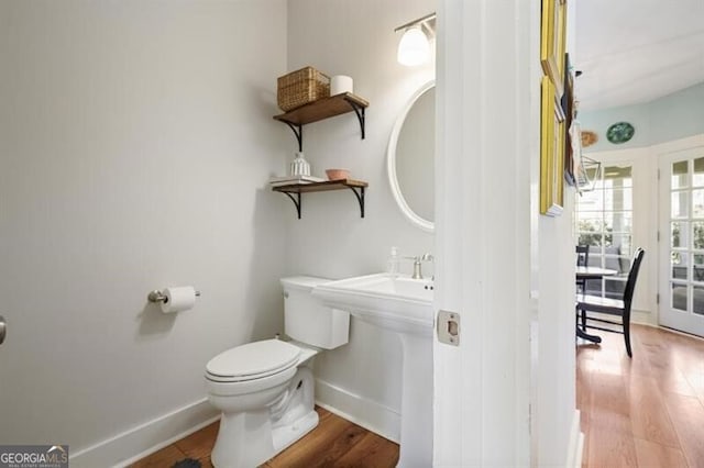 bathroom featuring toilet, wood finished floors, baseboards, and a sink