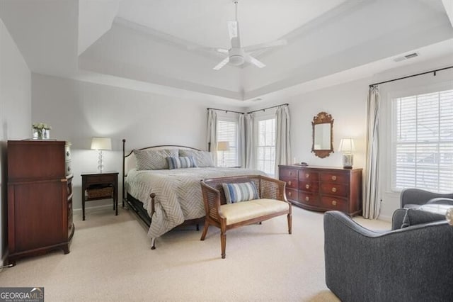 bedroom with visible vents, a raised ceiling, light carpet, and ceiling fan