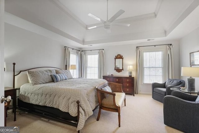 bedroom with multiple windows, a raised ceiling, and light carpet