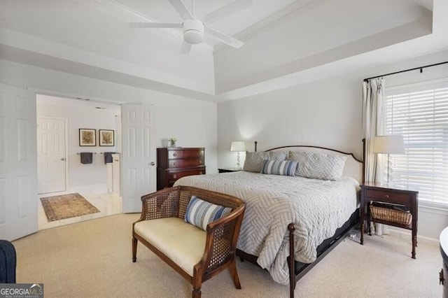 bedroom featuring multiple windows, a raised ceiling, and light carpet