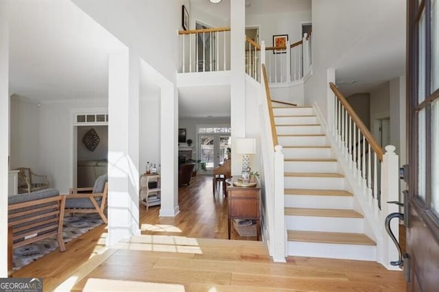 foyer entrance featuring wood finished floors, visible vents, a fireplace, stairs, and a towering ceiling