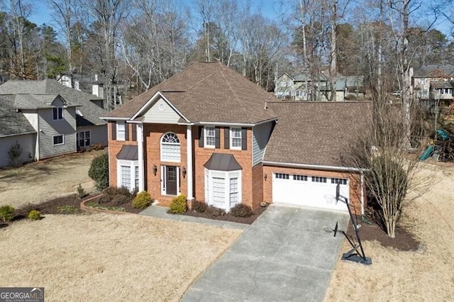 neoclassical home with brick siding, a garage, driveway, and a shingled roof