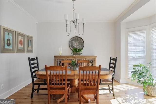 dining room with a chandelier, light wood-type flooring, baseboards, and ornamental molding