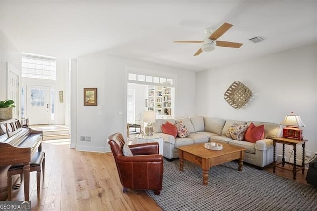 living room featuring visible vents, baseboards, light wood-style floors, and ceiling fan