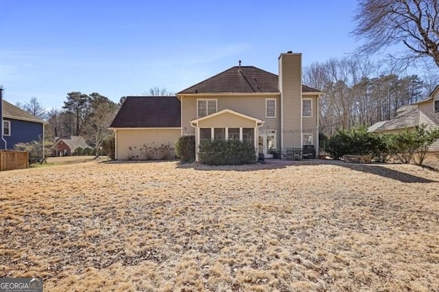 rear view of house with a chimney and a sunroom