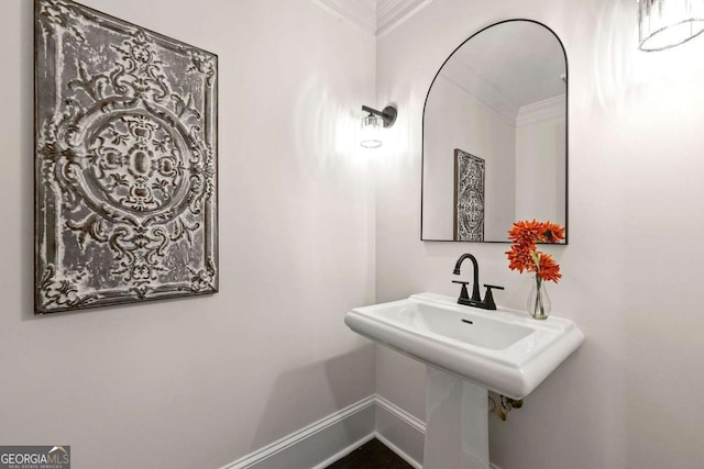 bathroom with a sink, baseboards, and crown molding