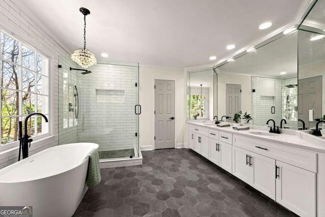 full bath with double vanity, crown molding, a shower stall, and a freestanding bath