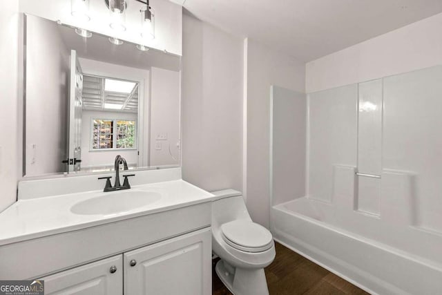 bathroom with toilet, vanity,  shower combination, and wood finished floors