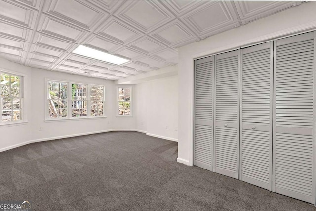 interior space featuring an ornate ceiling, baseboards, and dark colored carpet