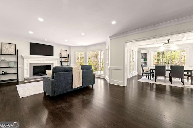 living area featuring dark wood finished floors, crown molding, beamed ceiling, and a fireplace with raised hearth