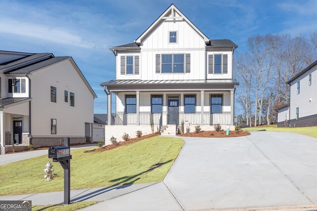 modern inspired farmhouse featuring metal roof, a standing seam roof, covered porch, board and batten siding, and a front yard