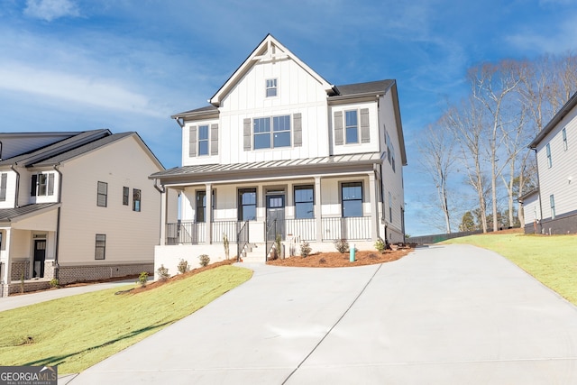 modern farmhouse featuring metal roof, a standing seam roof, a porch, board and batten siding, and a front yard