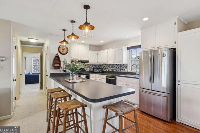 kitchen with dark countertops, a sink, and freestanding refrigerator