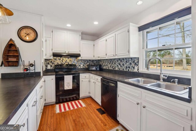 kitchen featuring tasteful backsplash, a sink, dark countertops, white cabinets, and black appliances