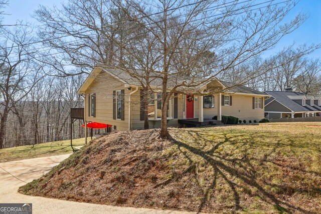 single story home with a front yard, concrete driveway, fence, and a chimney