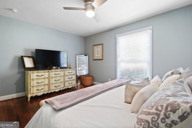 bedroom with dark wood-style floors, a ceiling fan, and baseboards